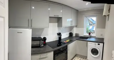 a kitchen with white cabinets and a washer and dryer at Charming 1-Bedroom Flat - Chelmsford City Centre in Chelmsford