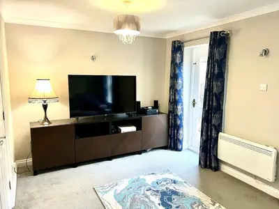 a living room with a flat screen tv on a entertainment center at Charming 1-Bedroom Flat - Chelmsford City Centre in Chelmsford