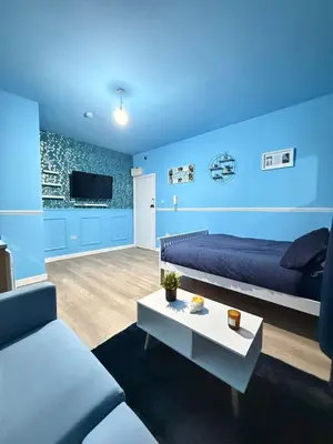 a blue room with a bed and a couch and a table at The Aqua Stay By Cambridge City Centre in Chesterton