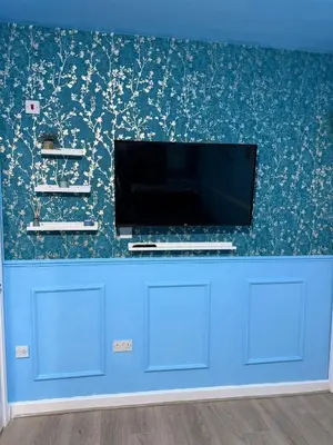 a flat screen tv on a blue wall with floral wallpaper at The Aqua Stay By Cambridge City Centre in Chesterton