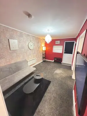 a living room with a couch and a clock on the wall at Quiet Blue Rooms By Cambridge City Centre in Chesterton