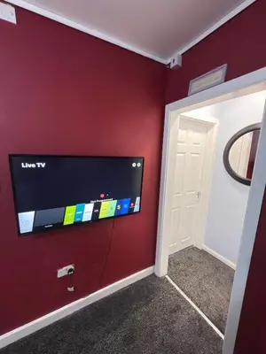 a room with a flat screen tv on a red wall at Quiet Blue Rooms By Cambridge City Centre in Chesterton