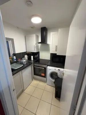a kitchen with white cabinets and a washer and dryer at Quiet Blue Rooms By Cambridge City Centre in Chesterton