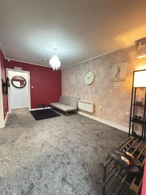 a living room with a couch and a clock on the wall at Quiet Blue Rooms By Cambridge City Centre in Chesterton