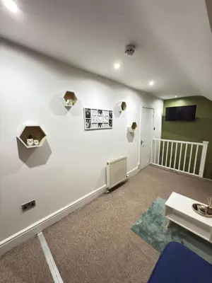 a living room with a white wall with shelves at The Traveller's Nest by Cambridge Central Station in Cambridge
