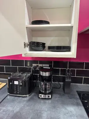 a kitchen counter with a coffee maker and plates in a cupboard at The Squid Escape By Cambridge Central Station in Cambridge