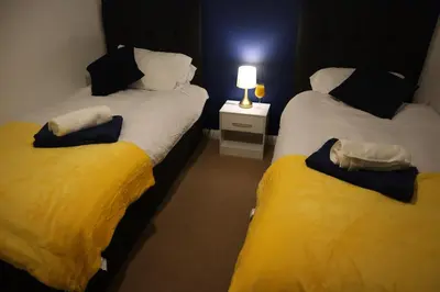 two beds in a room with a lamp on a table at Duxford Haven in Duxford