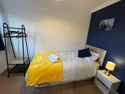 a bedroom with a bed with a yellow blanket at Duxford Haven in Duxford