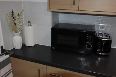 a kitchen counter with a black microwave and a vase at Duxford Haven in Duxford