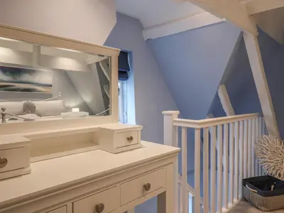 a room with a staircase with a large mirror at The Nutshell in Aldeburgh