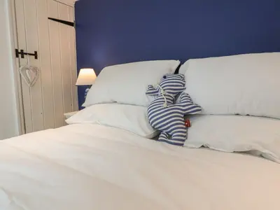 a bed with white sheets and pillows with at The Nutshell in Aldeburgh