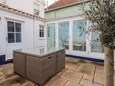 an outdoor patio with a glass table on a house at The Nutshell in Aldeburgh