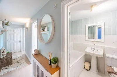 a bathroom with a sink and a tub and a mirror at 2 Truman Lodge in Thorpeness