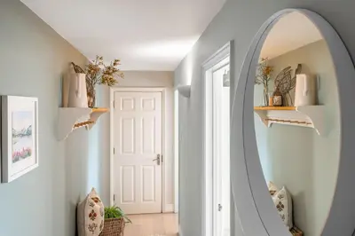 a hallway with an oval mirror and a white door at 2 Truman Lodge in Thorpeness