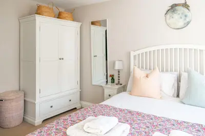 a bedroom with a white bed and white cabinets at 2 Truman Lodge in Thorpeness
