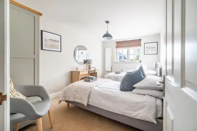 a bedroom with two beds and a chair at 2 Truman Lodge in Thorpeness