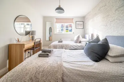 a bedroom with two beds and a desk and a mirror at 2 Truman Lodge in Thorpeness