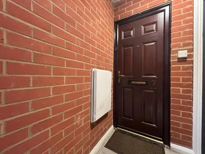 a black door with a mirror next to a brick wall at Canal Side Retreat in Maldon