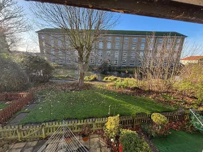 a garden in front of a building with a tree at Canal Side Retreat in Maldon
