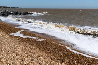 a sandy beach with waves coming in from the ocean at Serene Sands in Felixstowe