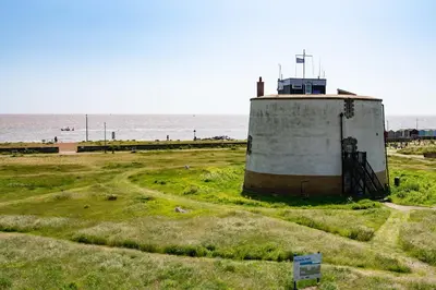 a lighthouse in a field next to the ocean at Serene Sands in Felixstowe