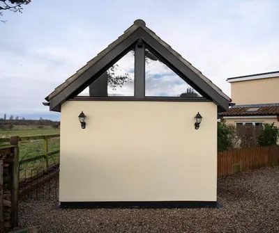 a large white garage with a triangular window at The Acorn - Roudham Norwich in Norwich