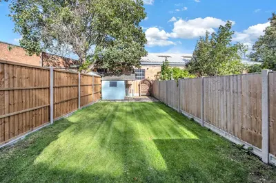 a backyard with a wooden fence and a gate at 10 Mustow St - Charming 3 bed home next to the Abbey Gardens in Bury St Edmunds in Bury Saint Edmunds