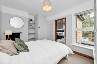 a white bedroom with a bed and a window at 10 Mustow St - Charming 3 bed home next to the Abbey Gardens in Bury St Edmunds in Bury Saint Edmunds