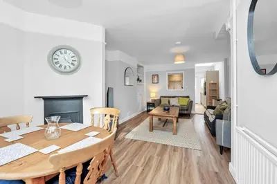 a dining room and living room with a table and a fireplace at 10 Mustow St - Charming 3 bed home next to the Abbey Gardens in Bury St Edmunds in Bury Saint Edmunds