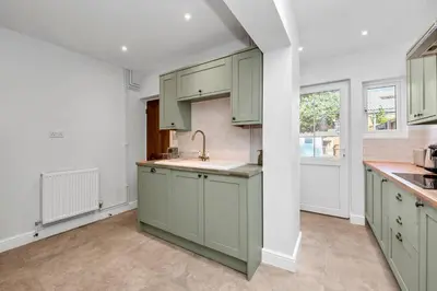 a kitchen with green cabinets and a sink at 10 Mustow St - Charming 3 bed home next to the Abbey Gardens in Bury St Edmunds in Bury Saint Edmunds