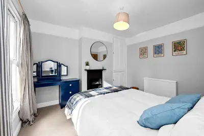 a bedroom with a bed with a blue dresser and a mirror at 10 Mustow St - Charming 3 bed home next to the Abbey Gardens in Bury St Edmunds in Bury Saint Edmunds