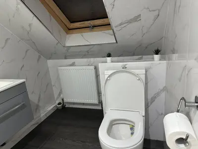 a white bathroom with a toilet with the lid up at A Cosy and Luxurious Studioflat in Navestock