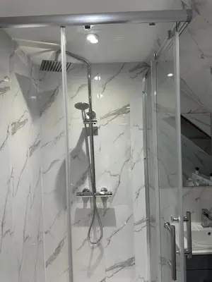 a shower in a bathroom with white marble at A Cosy and Luxurious Studioflat in Navestock