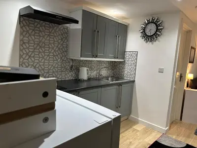 a kitchen with gray cabinets and a clock on the wall at A Cosy and Luxurious Studioflat in Navestock