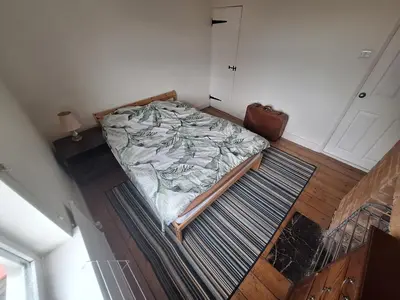 an unmade bed in a small room with a door at Room in Stowmarket in Stowmarket