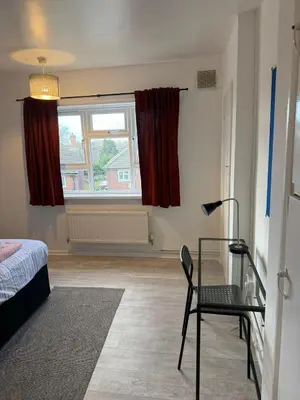 a room with a bed and a chair and a window at Cozy 3 Bedroom Flat near Essex Uni, WiFi and Free Parking in Hythe
