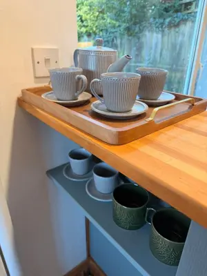a shelf with cups and saucers on it at The Grantchester - Charming 20th Century Home in Barton