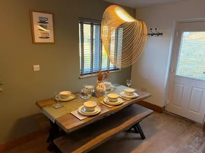 a dining room table with plates and glasses and a chandelier at The Grantchester - Charming 20th Century Home in Barton