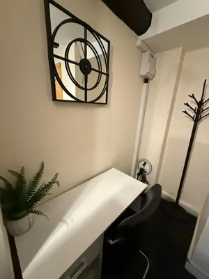 a room with a desk and a clock on the wall at Comfort zone in Colchester