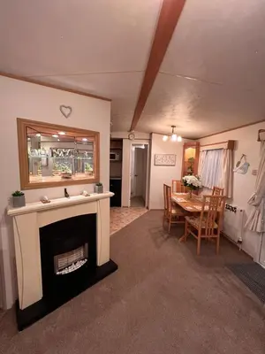 a living room with a fireplace and a table at A & C Coastal Hideaway with outside Decking in East Mersea