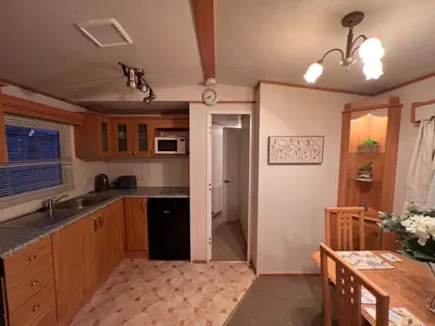 a kitchen with wooden cabinets and a table and a counter top at A and C Coastal Hideaway Private Decking in Colchester