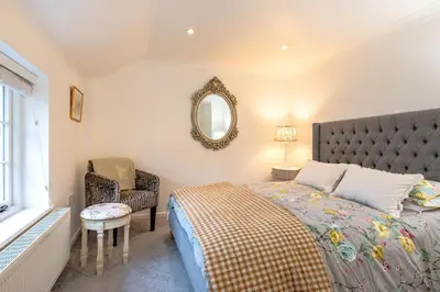 a bedroom with a bed and a chair and a mirror at 2 Bed in Scole oc-p34354 in Scole