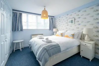 a blue bedroom with a bed and a table at 1 Ogilvie Lodge - A seafront apartment in Thorpeness - Close to Thorpeness Country Club - Managed by Aldeburgh Coastal Cottages in Thorpeness