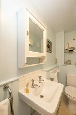 a white bathroom with a sink and a toilet at 1 Ogilvie Lodge - A seafront apartment in Thorpeness - Close to Thorpeness Country Club - Managed by Aldeburgh Coastal Cottages in Thorpeness