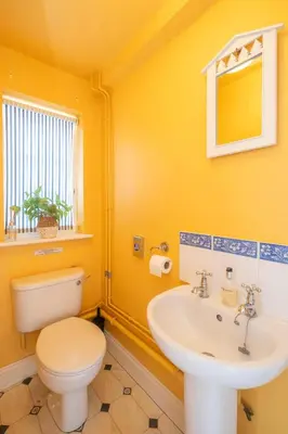 a yellow bathroom with a toilet and a sink at 1 Ogilvie Lodge - A seafront apartment in Thorpeness - Close to Thorpeness Country Club - Managed by Aldeburgh Coastal Cottages in Thorpeness