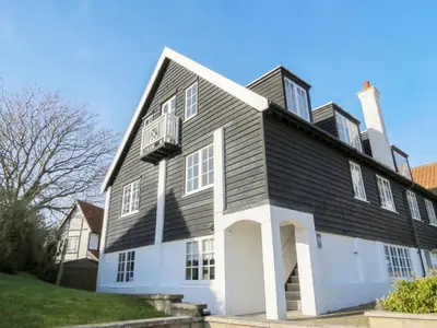 a large black and white house with a balcony at 1 Ogilvie Lodge - A seafront apartment in Thorpeness - Close to Thorpeness Country Club - Managed by Aldeburgh Coastal Cottages in Thorpeness