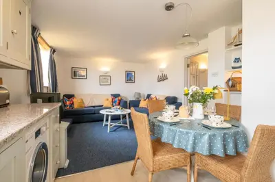 a kitchen and living room with a table and chairs at 1 Ogilvie Lodge - A seafront apartment in Thorpeness - Close to Thorpeness Country Club - Managed by Aldeburgh Coastal Cottages in Thorpeness