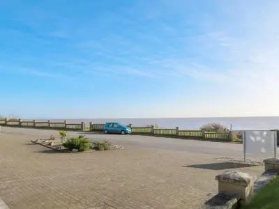 a blue van parked on a road next to the ocean at 1 Ogilvie Lodge - A seafront apartment in Thorpeness - Close to Thorpeness Country Club - Managed by Aldeburgh Coastal Cottages in Thorpeness