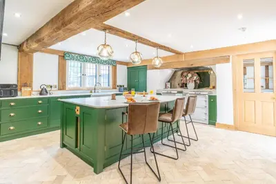 a kitchen with green cabinets and a table with chairs at 11 Bed in Stebbing oc-p34450 in Stebbing