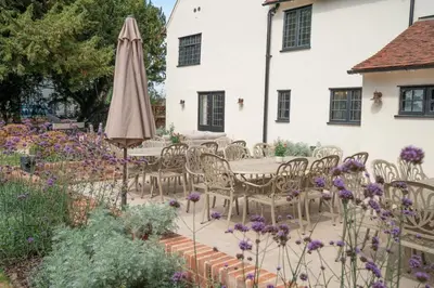 a patio with an umbrella and chairs and flowers at 11 Bed in Stebbing oc-p34450 in Stebbing